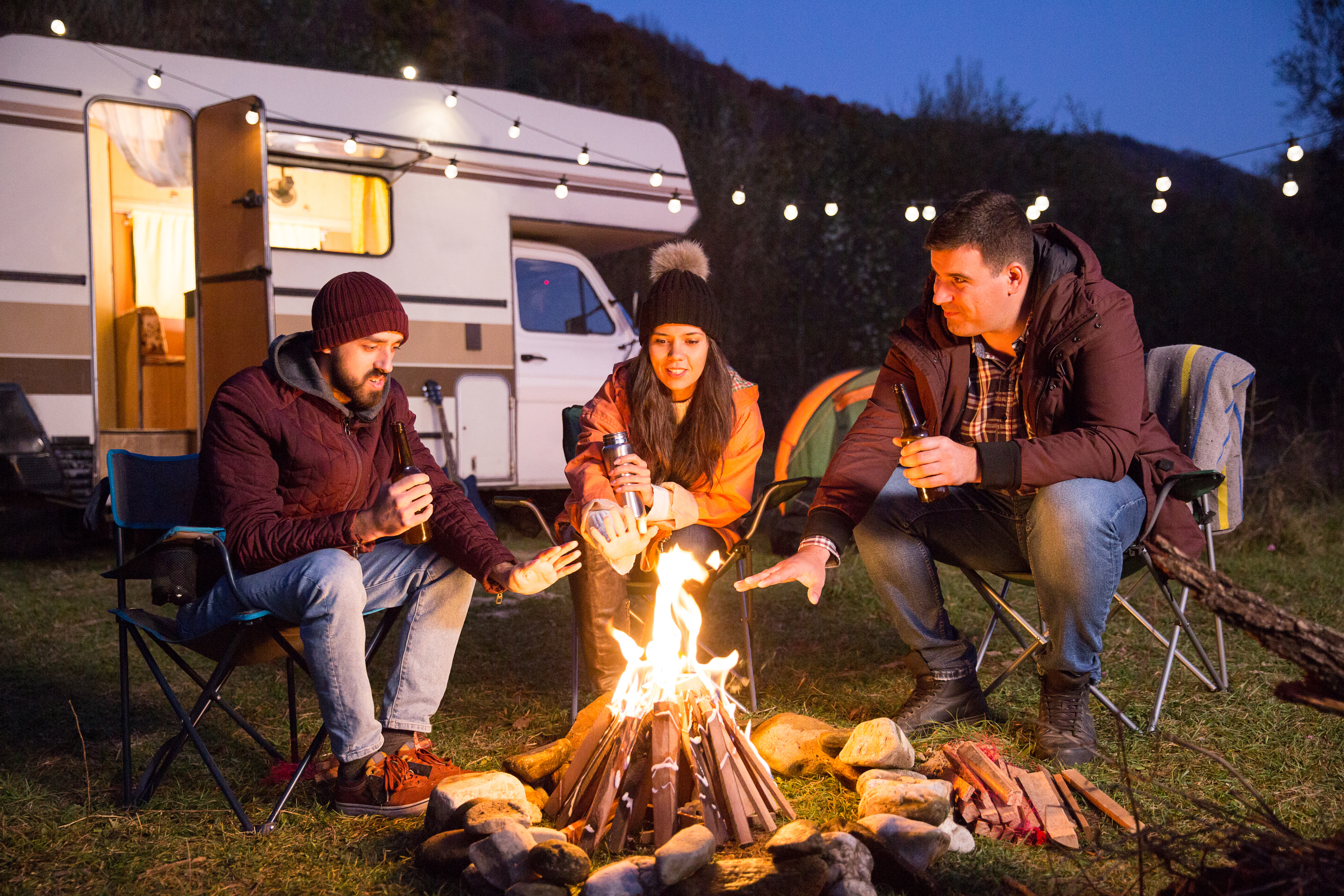 two males and a female around a campfire